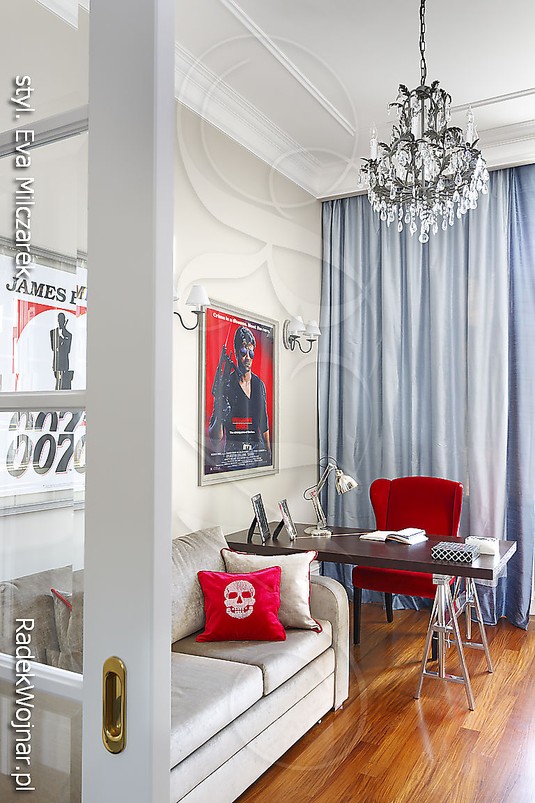 Gabinet z czerwonym fotelem, plakatami filmowymi i stylowym żyrandolem.