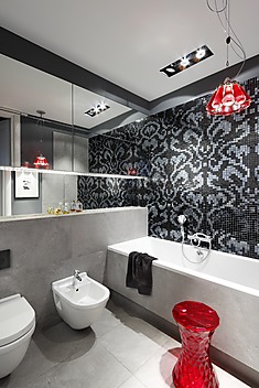 Łazienka z czarno białą mozaiką i czerwonym stołkiem Kartell i lampą z butelek