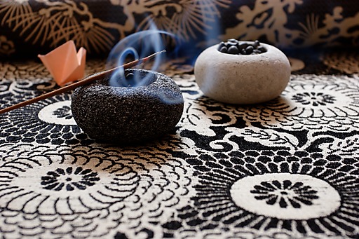 Detal wzorzystej tkaniny z dwoma kamiennymi świecznikami z sesji inspirowanej Japonią