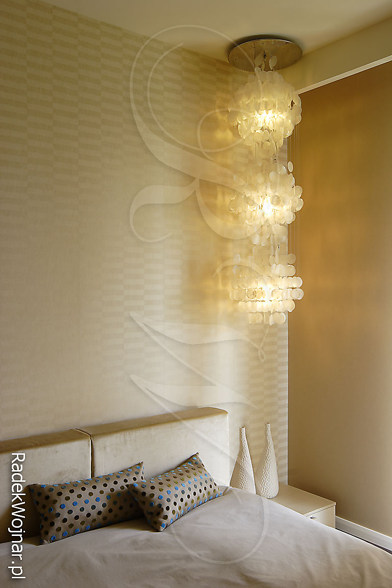 Monochromatyczna sypialnia z wiszącą lampą i złotym światłem