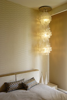Monochromatyczna sypialnia z wiszącą lampą i złotym światłem