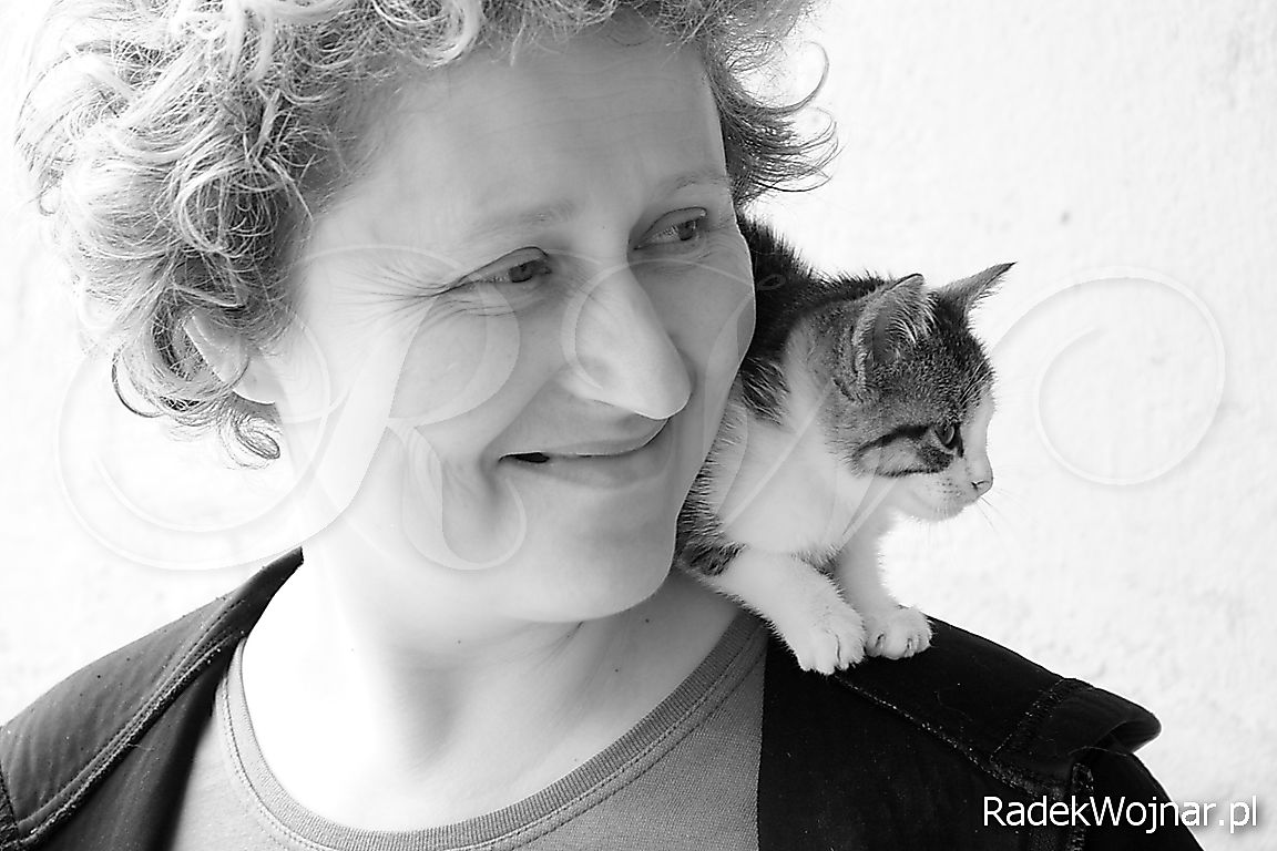 uśmiechnięta kobieta z kotkiem na ramieniu