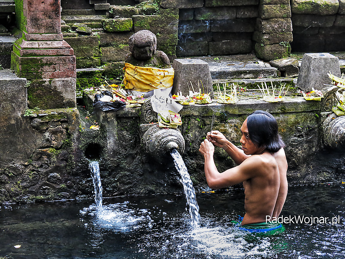 Indonezyjski pielgrzym składający ofiarę w świętych źródłach na Bali