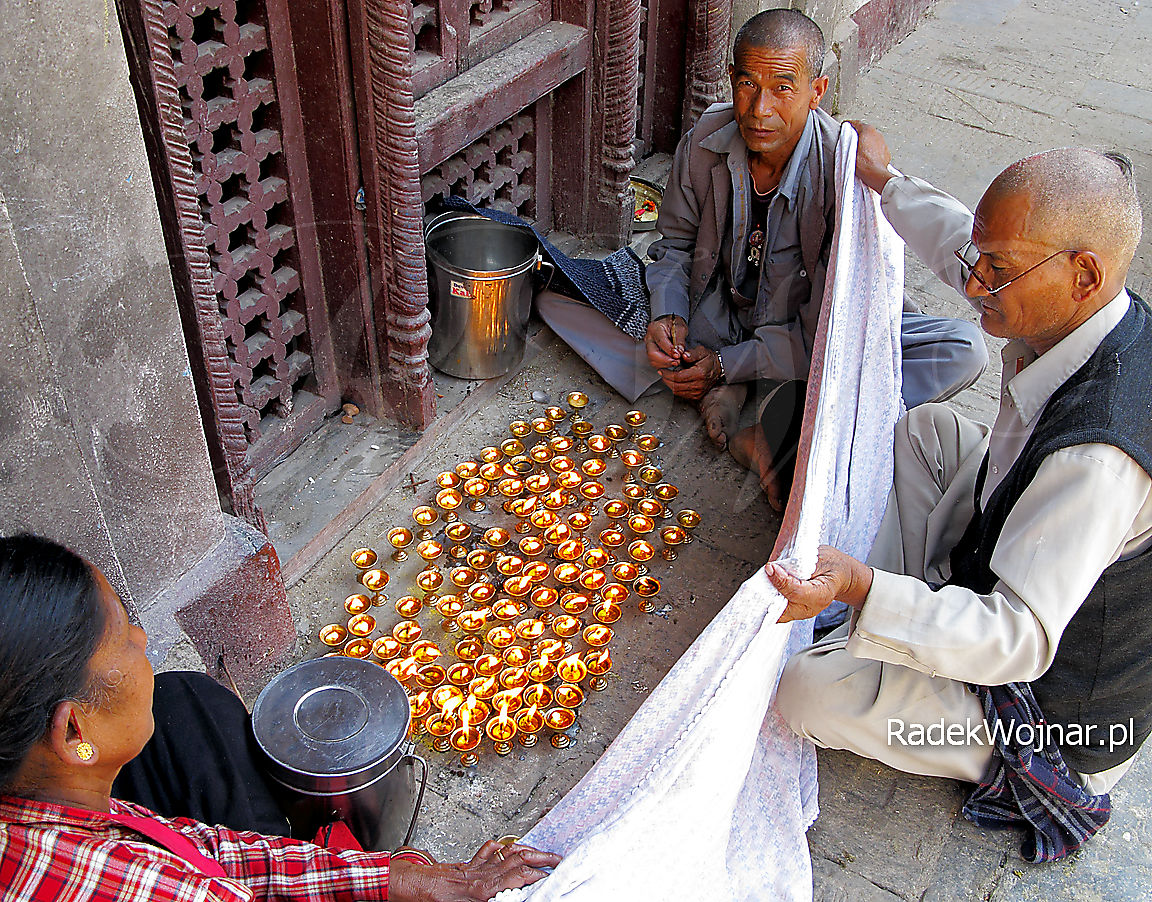 Lampki modlitewne osłaniane przed wiatrem przez bramina i pomocników, Nepal