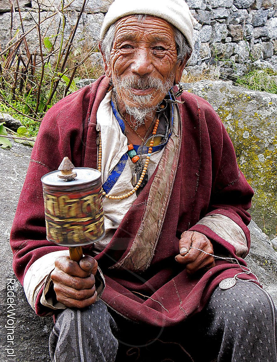 Starzec buddysta modli się używając młynka, zaraz poprosi o zapłatę