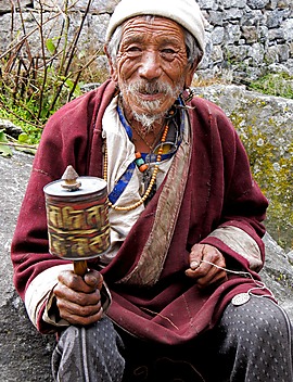 Starzec buddysta modli się używając młynka, zaraz poprosi o zapłatę
